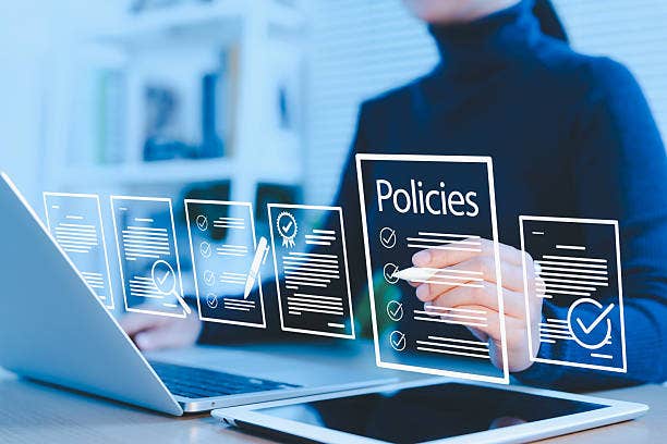 Policy documentation and compliance concept. Businesswoman reviews digital document Policies with icons, checklists, certifications, and financial detail. policy management, regulatory compliance,